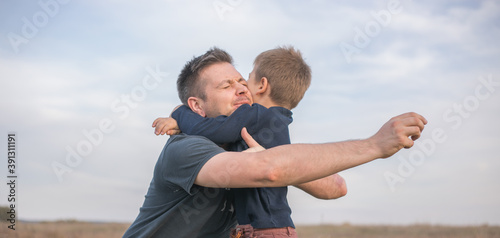 Happy son hugging dad on the  meadow background. Concept of father-son relationship © Maria