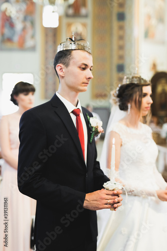 Bride and groom holding candles in church photo