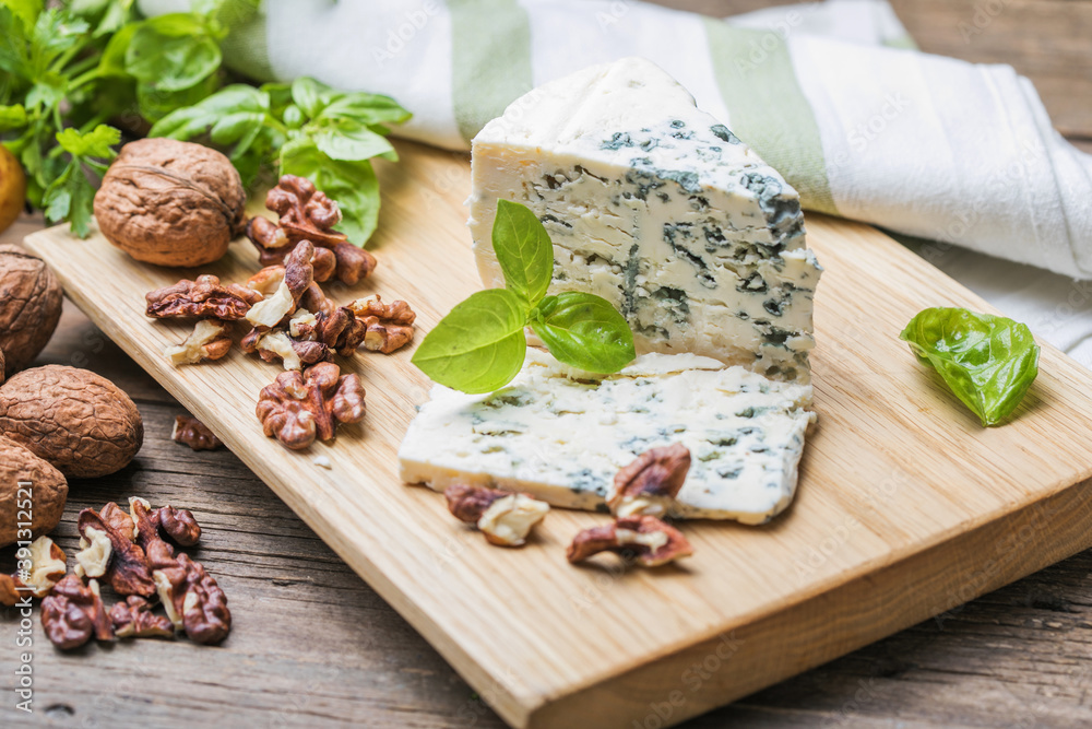Fototapeta premium Fourme d'ambert blue cheese and walnuts. Wooden background. Top view