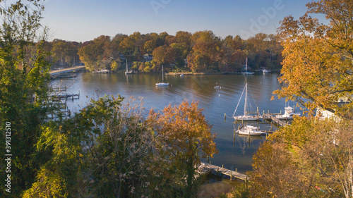 Fototapeta Naklejka Na Ścianę i Meble -  Aerial view of colorful sailboat moorings, docks,   and bright golden foliage on Weems Creek, in historic downtown Annapolis Maryland on a fall day