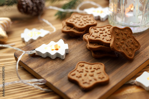 Homemade star-shaped Christmas cookies with cinnamon and ginger are placed on a wooden stand among the Christmas lights . side view