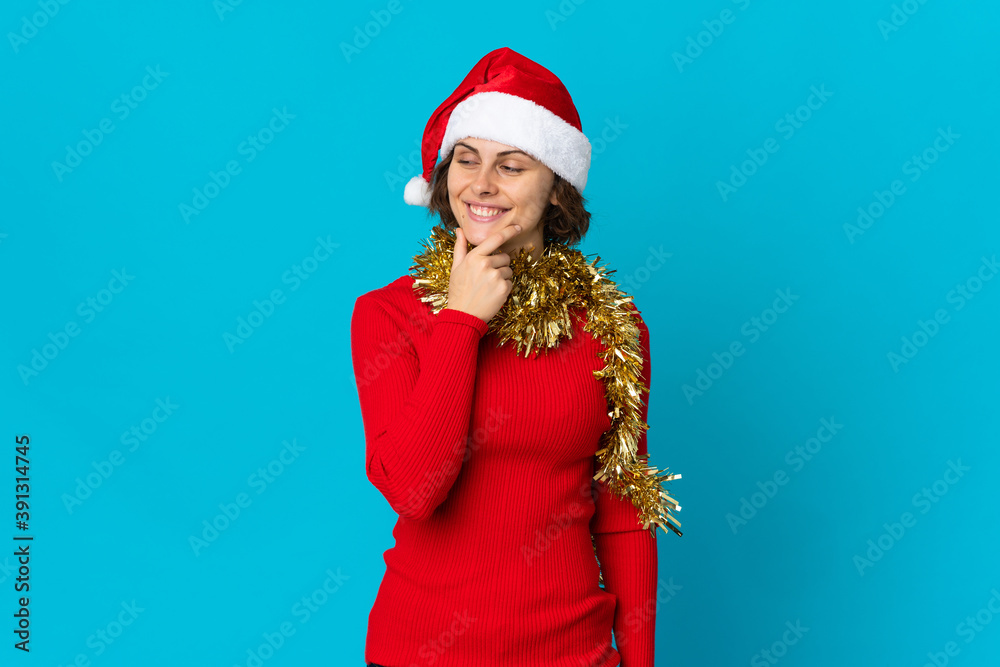 English girl with christmas hat isolated on blue background looking to the side and smiling English girl with christmas hat isolated on blue background looking to the side and smiling