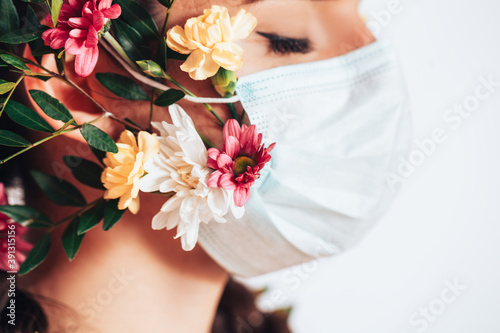 Fototapeta Naklejka Na Ścianę i Meble -  Young woman wearing a medical mask made of flowers during a pandemic.