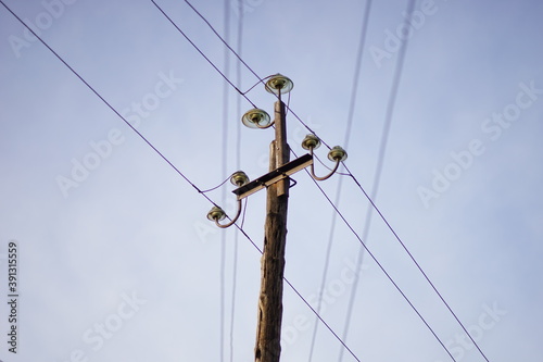 old wooden pillar with wires on clear blue sky background.