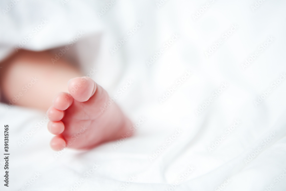 close up the foot of a asian newborn baby wearing a dress on white background close up the foot of a asian newborn baby wearing a dress on white background