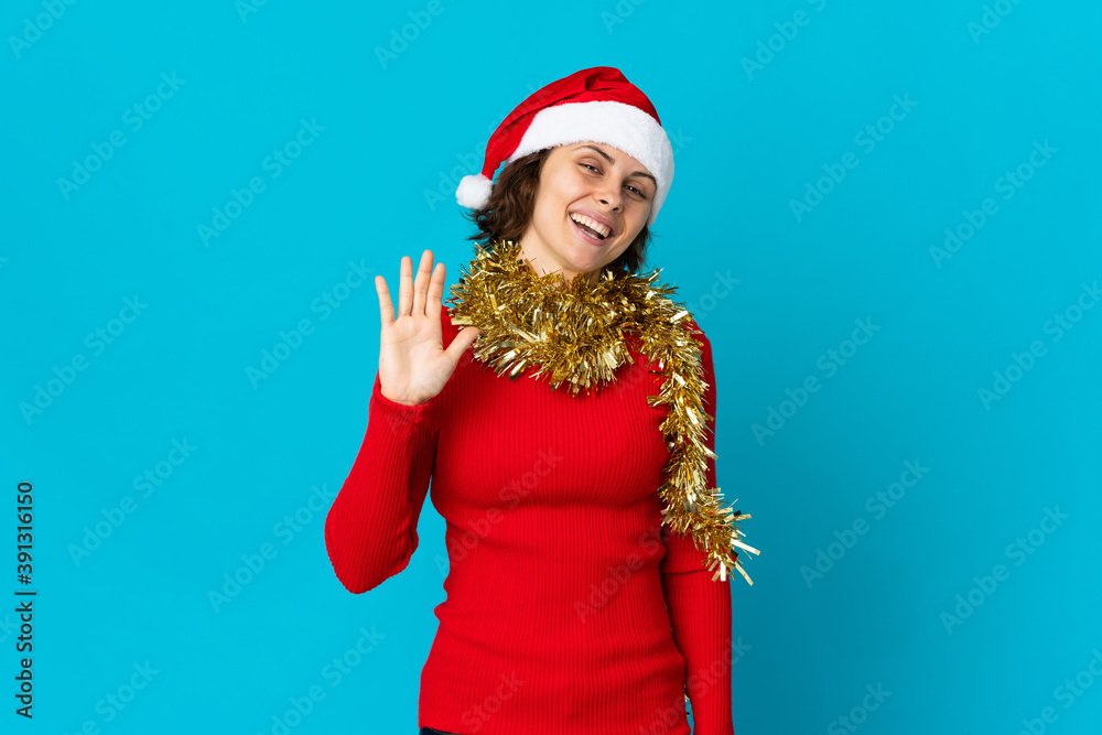 English girl with christmas hat isolated on blue background saluting with hand with happy expression English girl with christmas hat isolated on blue background saluting with hand with happy expression