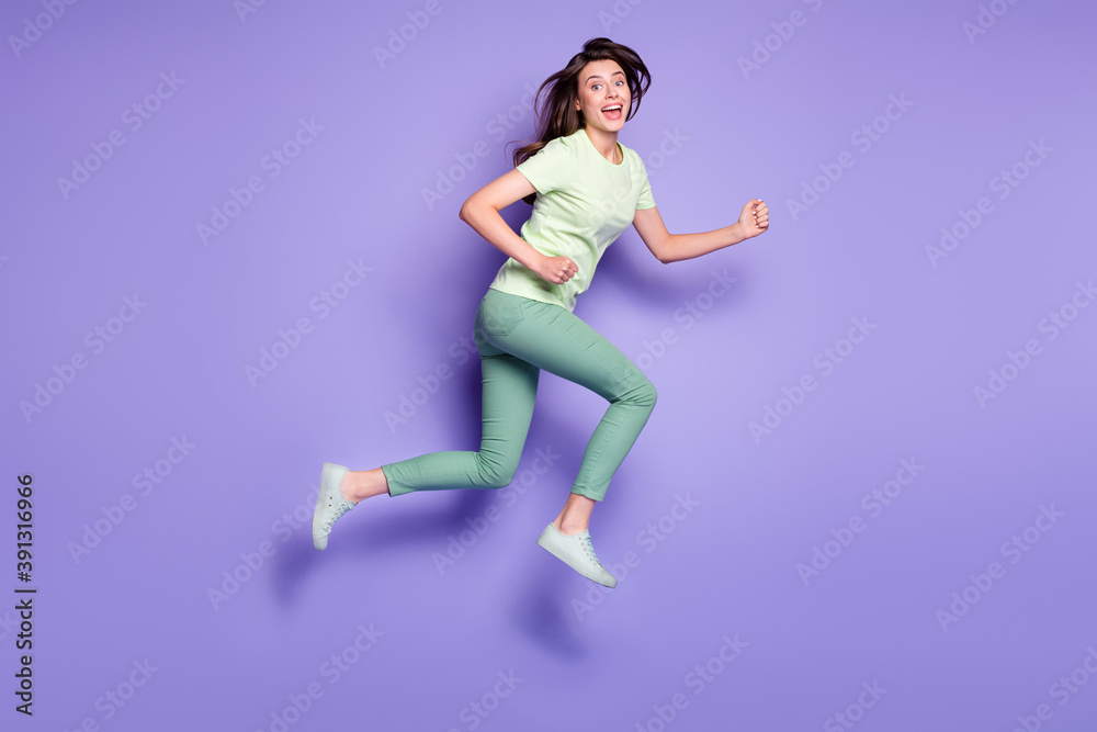 Photo portrait full body view of smiling girl running jumping up isolated on vivid violet colored background Photo portrait full body view of smiling girl running jumping up isolated on vivid violet colored background