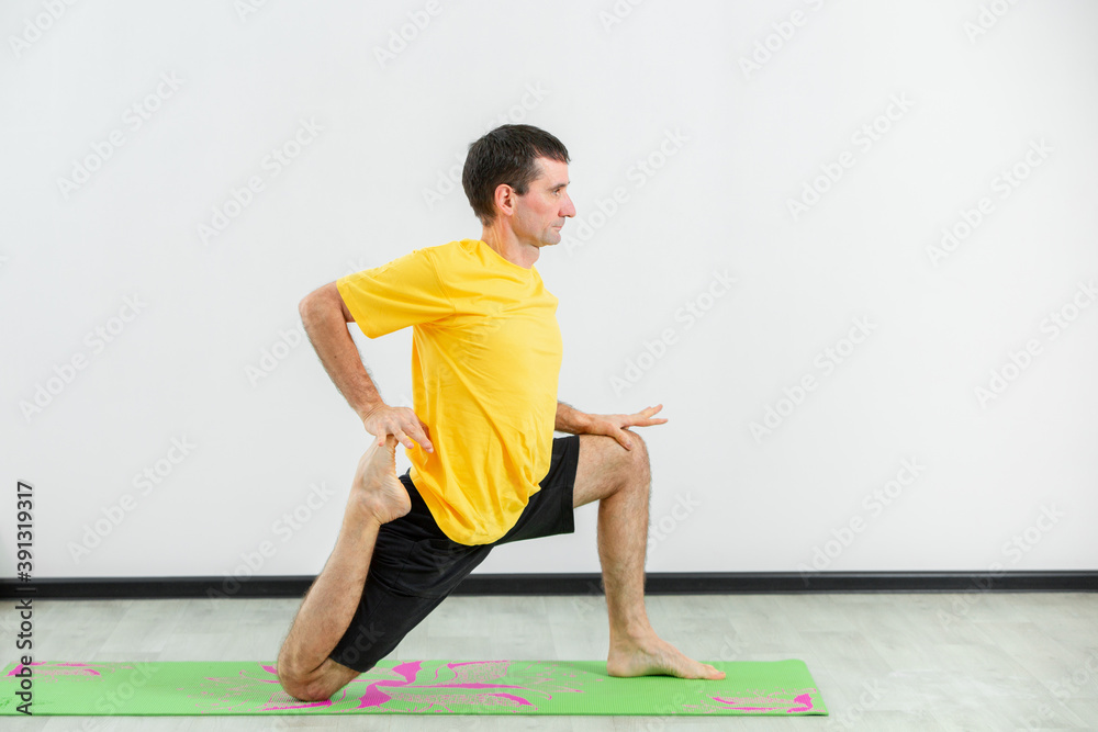 Experienced yogi doing seated forward bend yoga pose in gym. Man practicing yoga. Yogi concept. Side view.