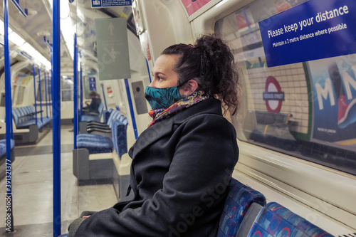 female passenger wearing face covering mask during covid-19 lockdown inside metro train in england uk photo