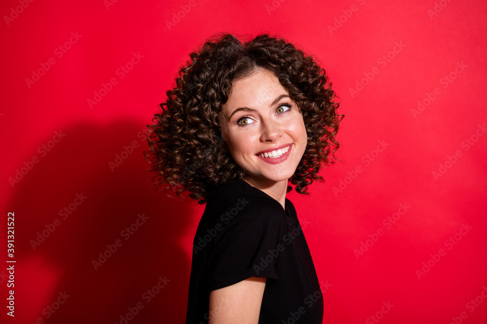 Photo portrait of smiling woman looking behind shoulder isolated on vivid red colored background Photo portrait of smiling woman looking behind shoulder isolated on vivid red colored background