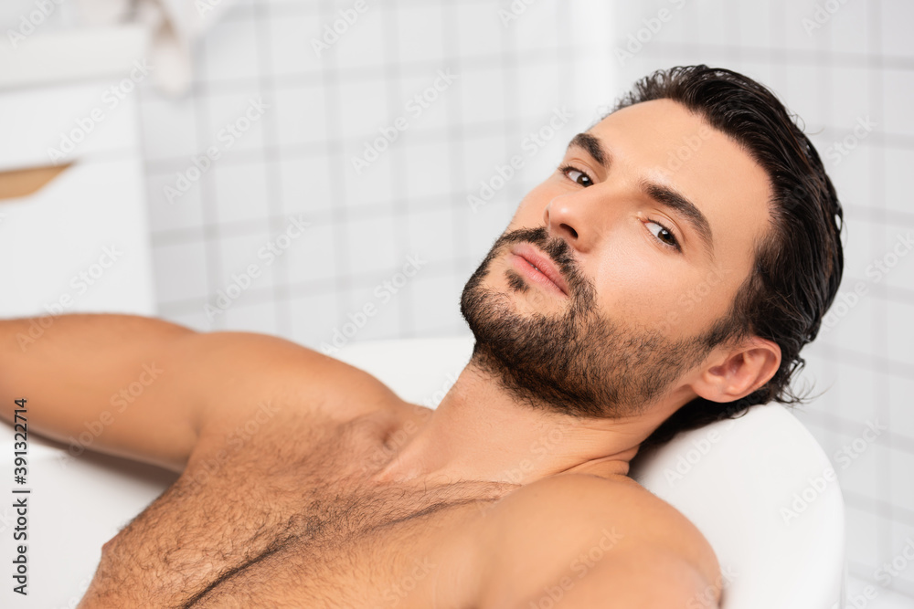 Obraz premium Bearded man looking at camera while taking bath