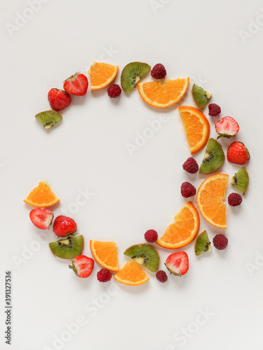 Fototapeta Naklejka Na Ścianę i Meble -  Creative arrangement of sliced fruits and berries arranged in a circle. Flat lay with copy space