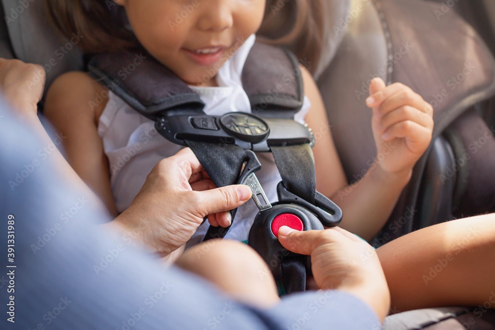 Parent buckling her child's seat belt in the car. Transportation safety.