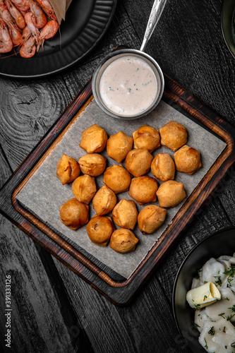 Deep-fried dumplings with garlic sauce on a background of black boards. Festive table with delicious food.