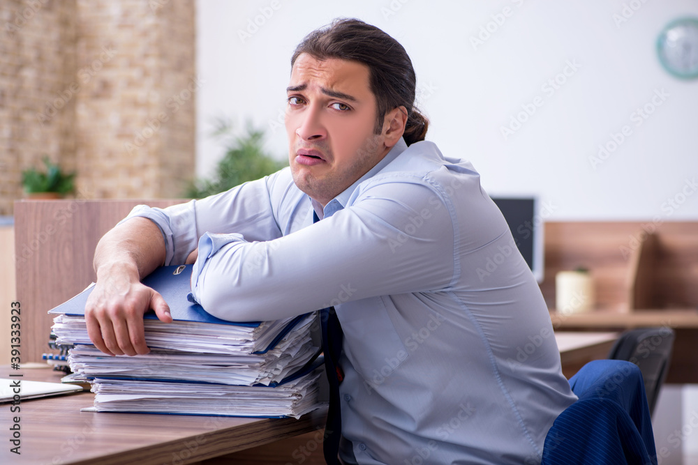 Young male employee unhappy with excessive work Young male employee unhappy with excessive work