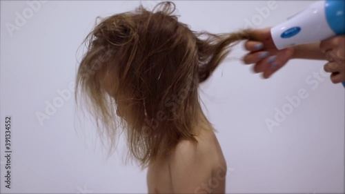 hair drying process. moms hands dries hair with hairdryer of cute happy little blonde daughter. hair care. parenting. FullHD footage.