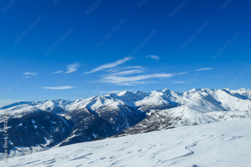A panoramic view on snow capped Alps in Austria, seen from Katschberg Ski Resort in Austria.The slopes are covered with fresh, powder snow. Idyllic winter landscape. Sunny day