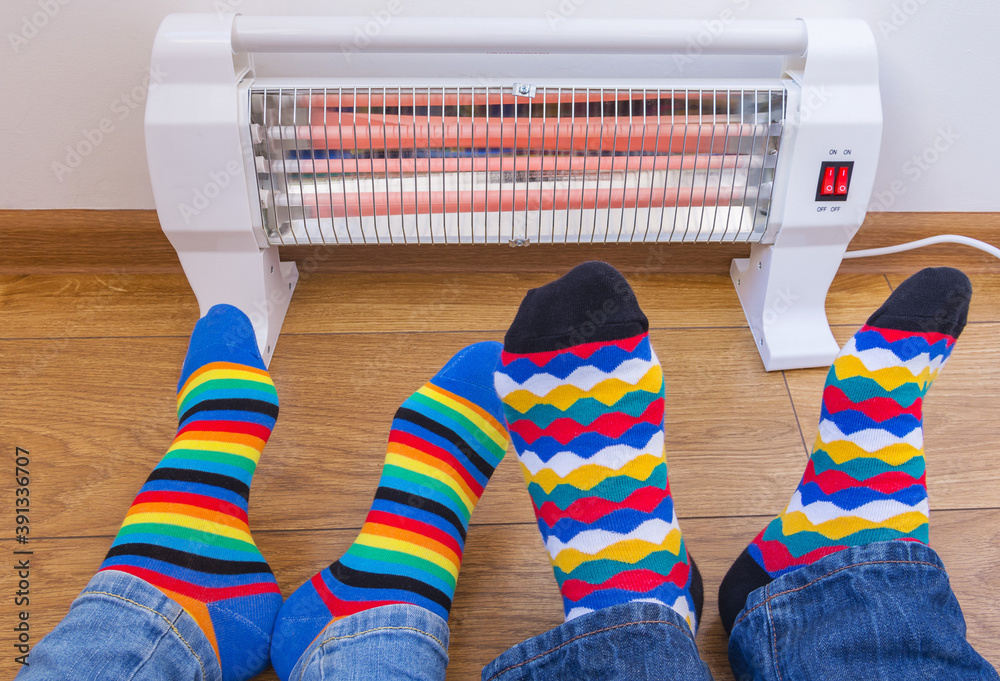 A young couple wearing bright rainbowcolored socks warms their cold