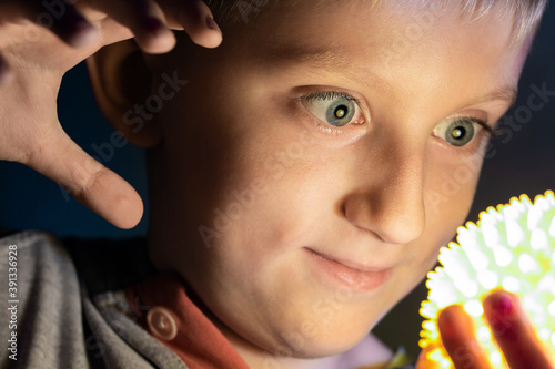 Boy is holding a glowing toy in his hands.