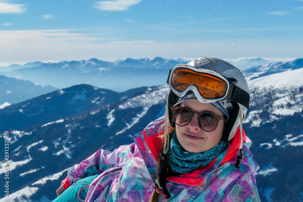 Close up on a woman enjoying the sunny, winter day in Austrian Alps on top of Katschberg Ski Resort. Panoramic view on the surrounding mountains. Winter wonderland. Sunny winter day. She wears a helm