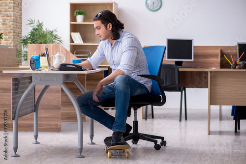 Young male employee with skateboard in the office