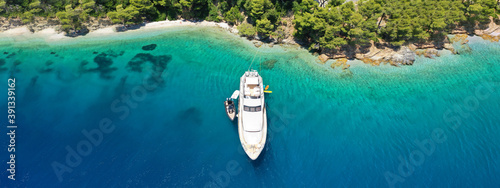 Aerial drone ultra wide panoramic photo of luxury yacht anchored in tropical exotic island with crystal clear turquoise sea and pine trees © aerial-drone