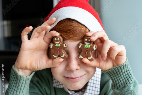 Horizontal portrait of little kid eating Christmas chocolate cookies at home. Home made sweet cookies for Christmas season. Family with kids lifestyle.