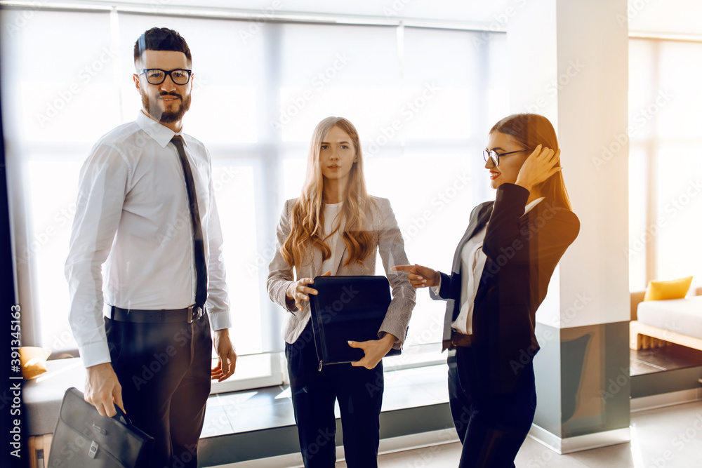 Fototapeta premium Group of modern business people standing in a glazed hall of an office building