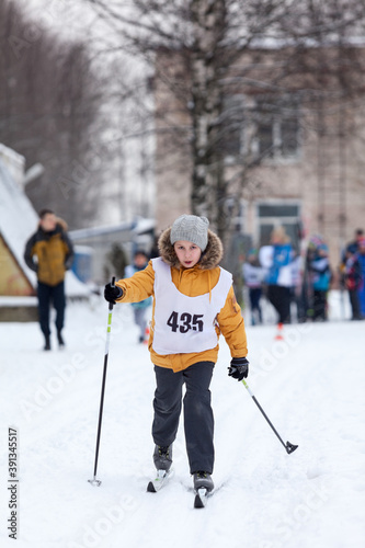 Young Caucasian girl running cross-country ski at competition, winter activities