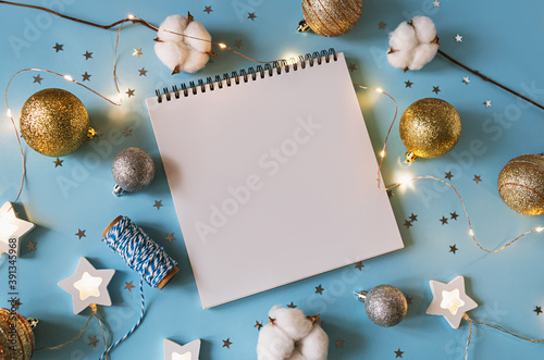 Christmas festive decorations and notebook. With wish list and 2022 goals concept. Notebook mock up, gift, and coton branch with shiny golden balls.New year flat lay, top view, copy space. photo