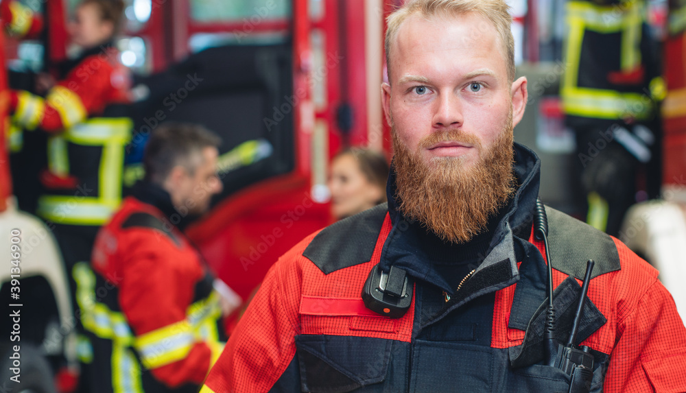 Young and determined fire fighter with team working in the background