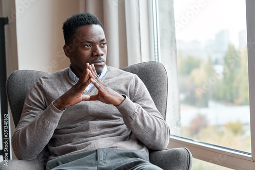 Photography Confident serious focused stylish rich african black man sitting in chair at home looking away through window dreaming thinking of success, leadership, business vision, planning future in luxury life