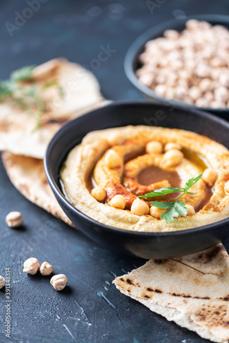 Hummus, chickpea dip, olive oil, raw beans, smoked paprika, pita on dark authentic background. Middle eastern, jewish cuisine or arabic dishes. Top view. Copy space. Vegan, vegetarian food concept