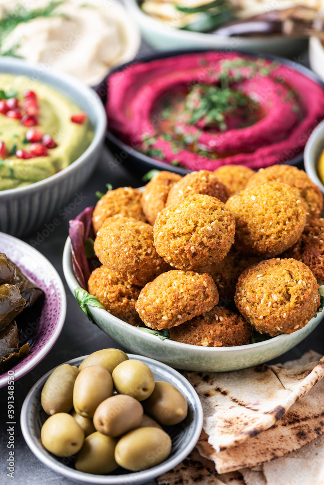 Arabic traditional cuisine. Middle Eastern meze with pita, olives, colorful hummus, falafel, stuffed dolma, babaganush, pickles, vegetables, pomegranate, eggplants. Mediterranean appetizer party idea Arabic traditional cuisine. Middle Eastern meze with pita, olives, colorful hummus, falafel, stuffed dolma, babaganush, pickles, vegetables, pomegranate, eggplants. Mediterranean appetizer party idea