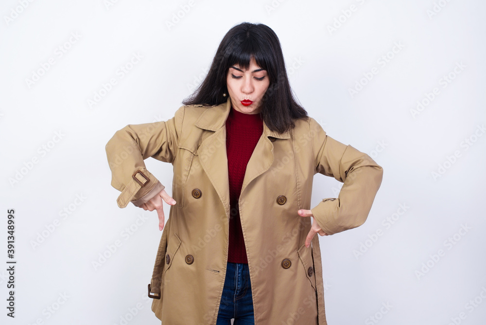Charming happy young surprised woman, points down with both index fingers, wears coat, enjoys something pleasant on floor, models against white background. Promotion concept.
Charming happy young surprised woman, points down with both index fingers, wears coat, enjoys something pleasant on floor, models against white background. Promotion concept.