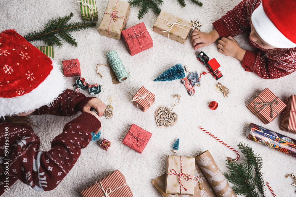 two children at home on the carpet lay out Christmas gifts. two children at home on the carpet lay out Christmas gifts.