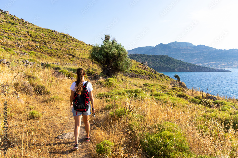 Woman walking on scenic seashore, Lesbos, Greece