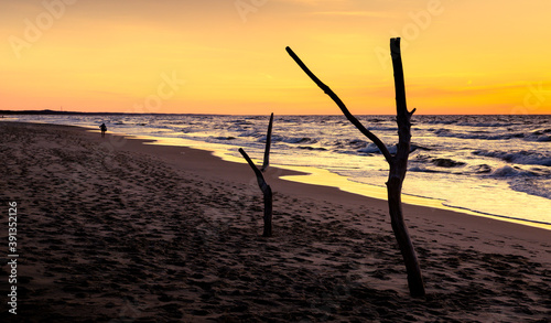 Sunset by the sea. Sandy waves and small quiet waves. Calm sea.