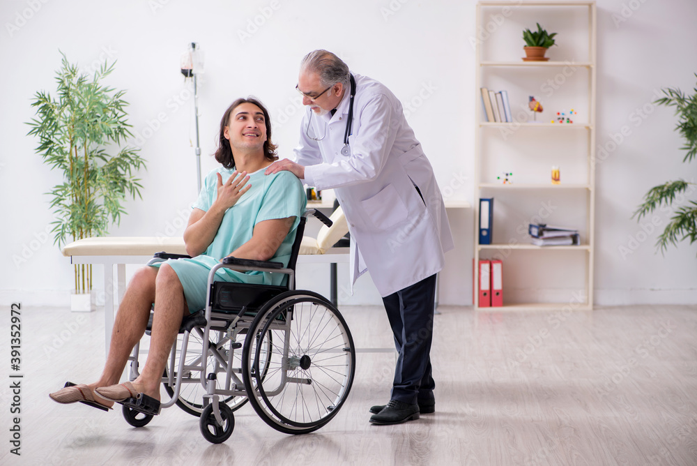 Young male patient in wheel-chair and experienced doctor traumatologist Young male patient in wheel-chair and experienced doctor traumatologist