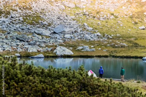 Man and woman are standing near the tent. Lake and camping in the Carpathian mountains.