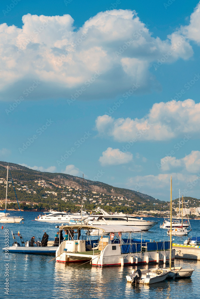 many small and medium yachts in a quiet bay of the Spanish city of Magaluf. A group of people board a yacht for diving