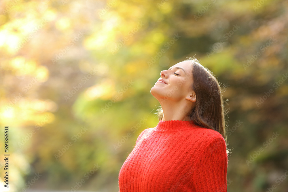 Woman in red breathing fresh air in autumn in a forest - obrazy, fototapety, plakaty 
