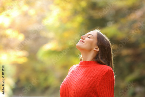 Woman in red breathing fresh air in autumn in a forest photo