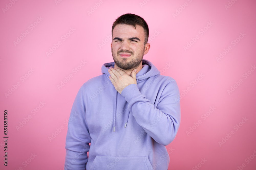 Fototapeta premium Young handsome man wearing casual sweatshirt over isolated pink background touching painful neck, sore throat for flu, clod and infection