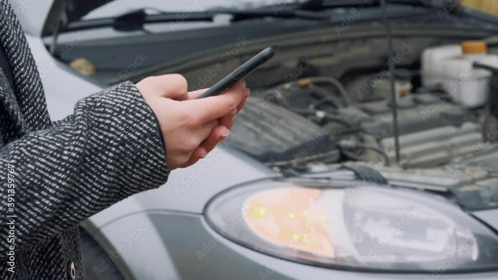 Young woman messaging someone in front of crashed car, close up Young woman messaging someone in front of crashed car, close up