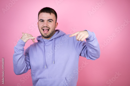 Young handsome man wearing casual sweatshirt over isolated pink background doing the “call me” gesture with her hands.