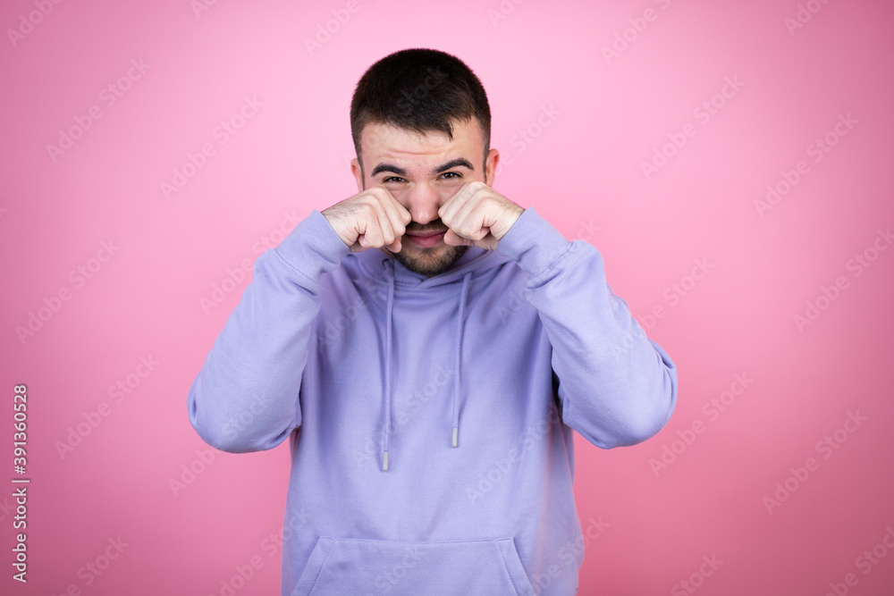 Young handsome man wearing casual sweatshirt over isolated pink background depressed and worry for distress, crying angry and afraid. Sad expression. Young handsome man wearing casual sweatshirt over isolated pink background depressed and worry for distress, crying angry and afraid. Sad expression.