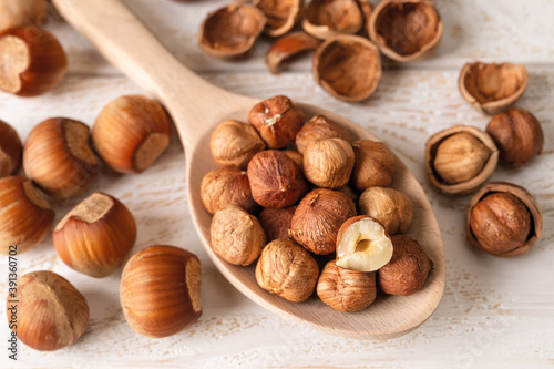 Hazelnut kernels in a large wood spoon over white wood table. Healthy vegetarian eating, antioxidant and protein source. Ketogenic and raw food diets ingredient.