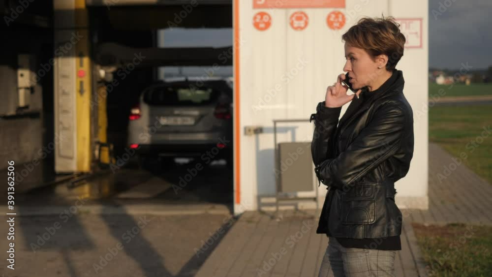 Attractive girl talking on the phone in the background of a car wash. Attractive girl talking on the phone in the background of a car wash.