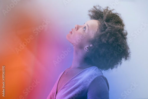 Portrait of woman with afro in multi colored light looking up photo